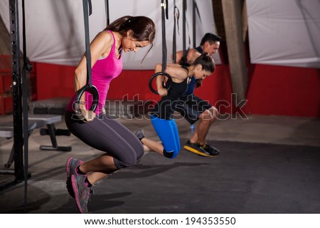 Group of people trying to pull their weight up using gymnastic rings in a cross-training gym