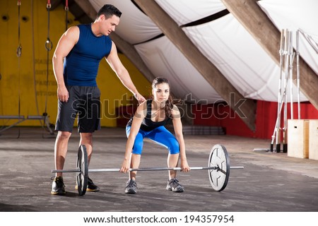 Cute young brunette getting some tips on her workout from her personal trainer at a gym