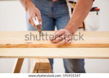Closeup of a contractor using a hammer to nail a wood board in place