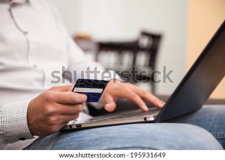 Closeup of a man using his credit card and laptop to buy some stuff online