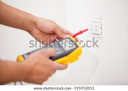 Closeup of a man using a multimeter to measure the output of a power outlet