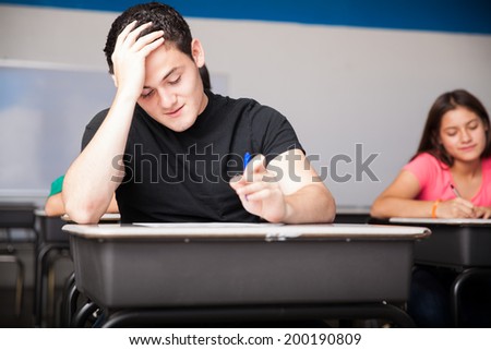 Portrait of an attractive teen having trouble solving a test in high school