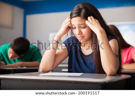 Cute girl looking worried while taking a test in a classroom