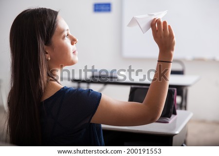Cute teen about to throw a paper plane during high school detention