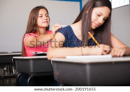Couple of high school teens exchanging notes during class