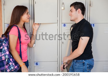 Couple of high schoolers flirting with each other next to the school lockers
