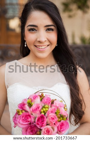 Beautiful portrait of a young bride holding a rose bouquet outside a church