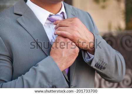 Closeup of a businessman getting ready and fixing his tie