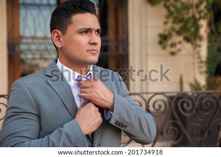 Portrait of an attractive groom getting ready for his wedding and fixing his tie