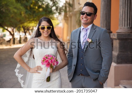 Cool bride and groom having fun and wearing sunglasses outside a church