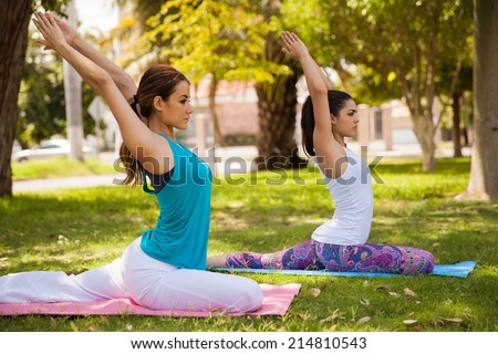 Beautiful female friends practicing yoga together at a park