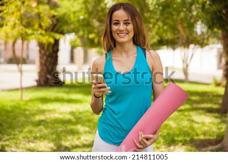Cheerful young woman social networking on her mobile phone during her yoga practice