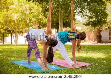 Young female friends working out and doing yoga outdoors