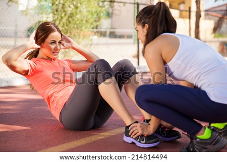 Cute girl working on her abs with the help of a friend