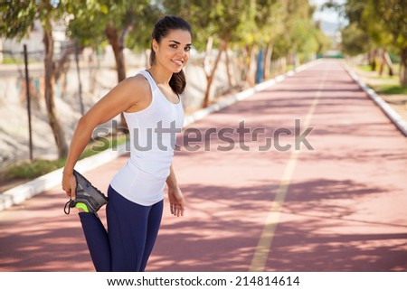 Gorgeous female runner stretching her legs before going for a run at the track
