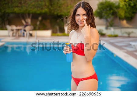 Portrait of a cute young Hispanic woman in a bikini wearing suntan and smiling