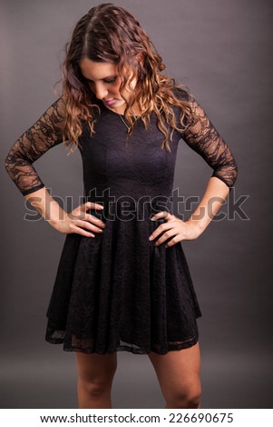 Studio portrait of a young Latin girl wearing a black dress on a gray background