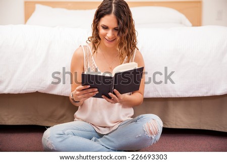 Pretty young brunette enjoying a good read while relaxing at home in her bedroom
