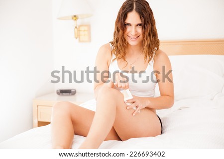 Pretty young woman using some wax to remove her hair from her legs at home