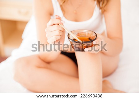 Closeup of a beautiful young woman preparing some wax to remove her body hair at home