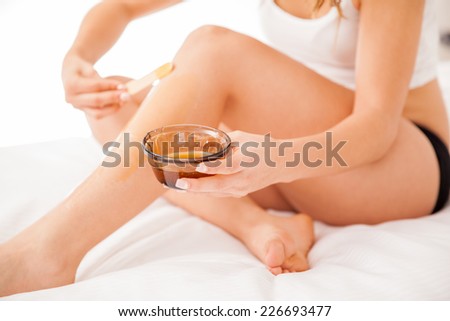 Young woman with beautiful legs putting some wax on them to remove all their hair
