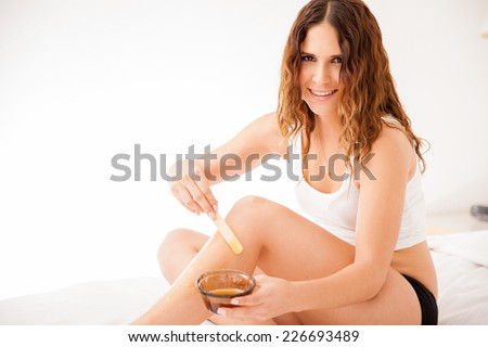 Cute young woman applying some hot wax on her legs to remove all unwanted hair