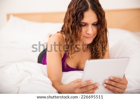 Beautiful Hispanic brunette reading on a tablet computer before going to sleep