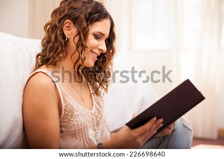Pretty young Hispanic woman enjoying a good read and relaxing at home