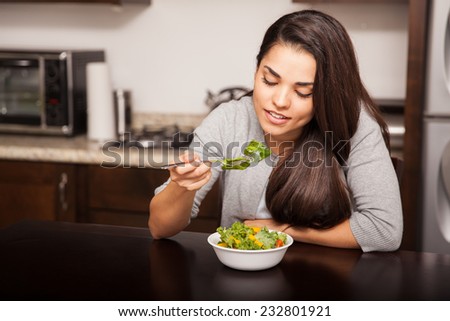Cute young brunette having a bite of a salad while eating lunch at home