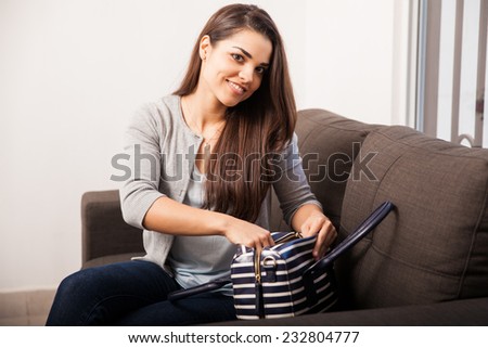 Beautiful young woman organizing and sorting thins inside her purse before going out