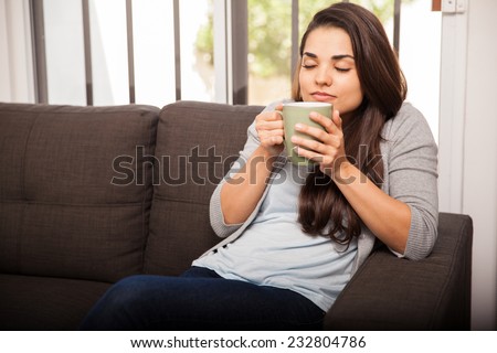 Pretty young brunette relaxing at home and enjoying the smell of her coffee