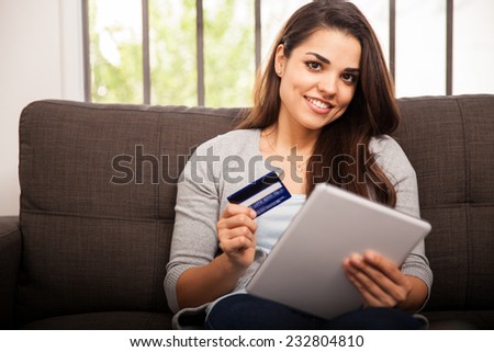 Gorgeous girl using her tablet computer and credit card to buy some stuff online