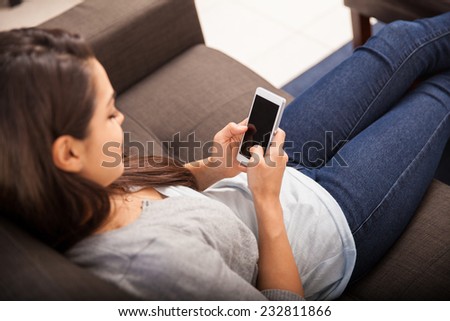 Point of view of a young woman using a smart phone for social networking. Focus on the phone