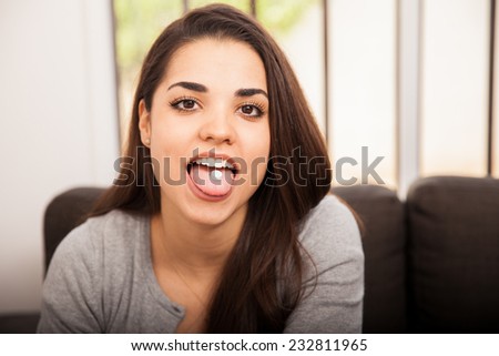 Cute Hispanic young woman sticking her tongue out with pill on it