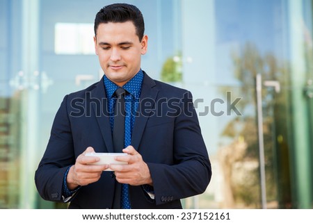 Portrait of a young Hispanic businessman using a cell phone to send emails and text messages