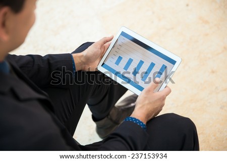 Point of view of a businessman using a tablet computer to analyze some performance charts
