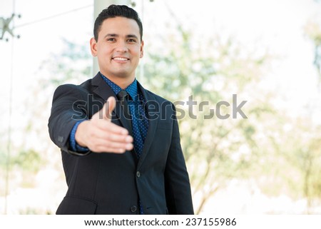 Attractive Hispanic businessman extending his hand for a handshake and smiling