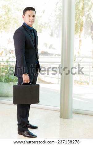 Full length view of a young Latin businessman carrying a briefcase