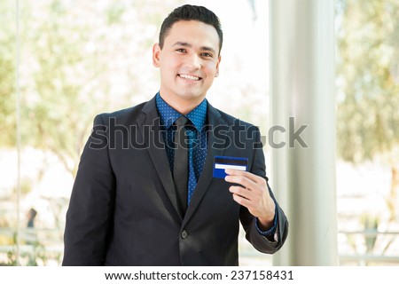 Handsome young financial adviser presenting a new credit card and smiling