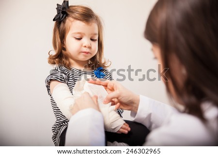 Portrait of a beautiful little girl at the doctor\'s office getting her arm fixed with a bandage