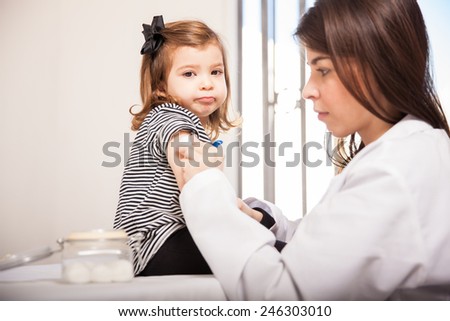 Portrait of a cute little girl looking scared while her doctor prepares her for a vaccination