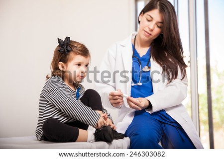Little girl waiting in a doctor\'s office while a doctor reads her temperature from a thermometer