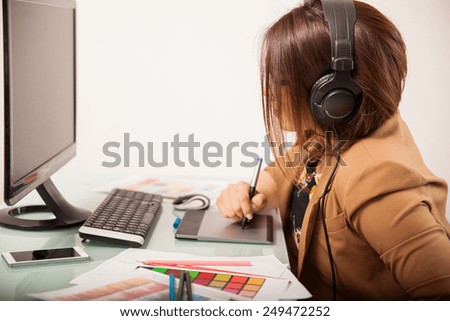 Profile view of a female graphic designer doing some work while listening to music with headphones