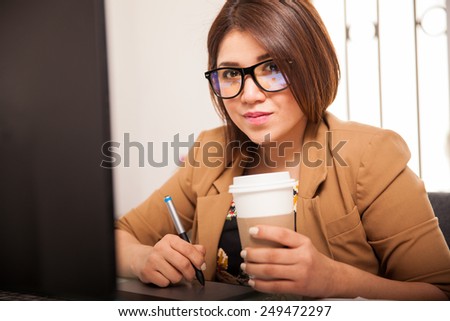 Portrait of a beautiful retoucher with glasses enjoying a cup of coffee at work