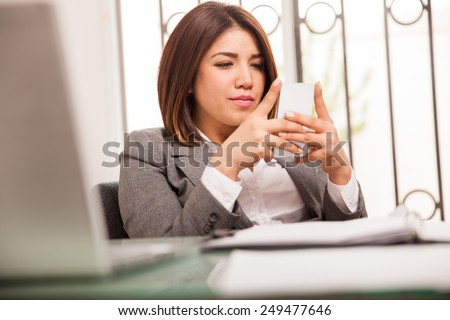 Attractive young business woman reading emails and working on her cell phone