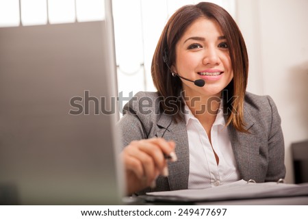Beautiful young woman in a suit wearing a headset and taking calls from customers