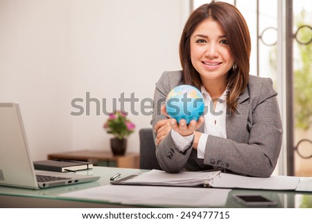Portrait of a pretty mixed-race business woman holding a small globe to convey she works for an international company