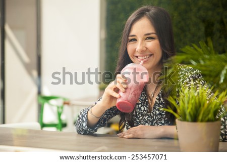 Cute young Hispanic woman taking a smoothie break at a juice bar