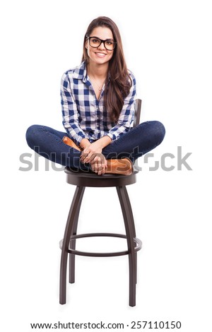 Attractive young Hispanic girl sitting on a chair with her feet up and smiling