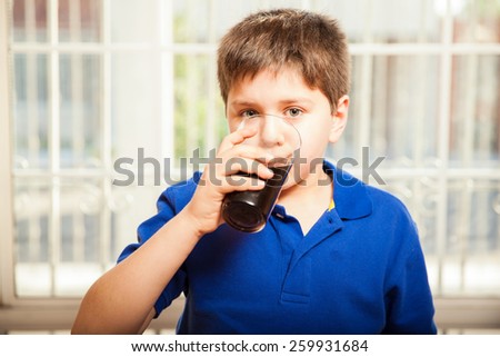 Portrait of a young boy drinking soda from a glass at home